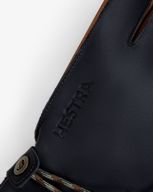 Close-up of navy blue leather Wakayama Gloves featuring an embossed logo and a wrist cord with a metal eyelet.