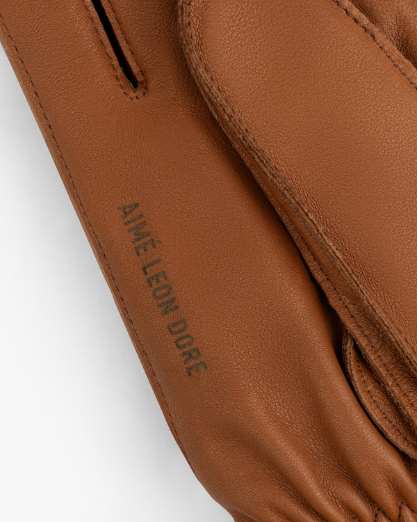 Brown leather Wakayama Gloves with the text Aimé Leon Dore embossed on the cuff.