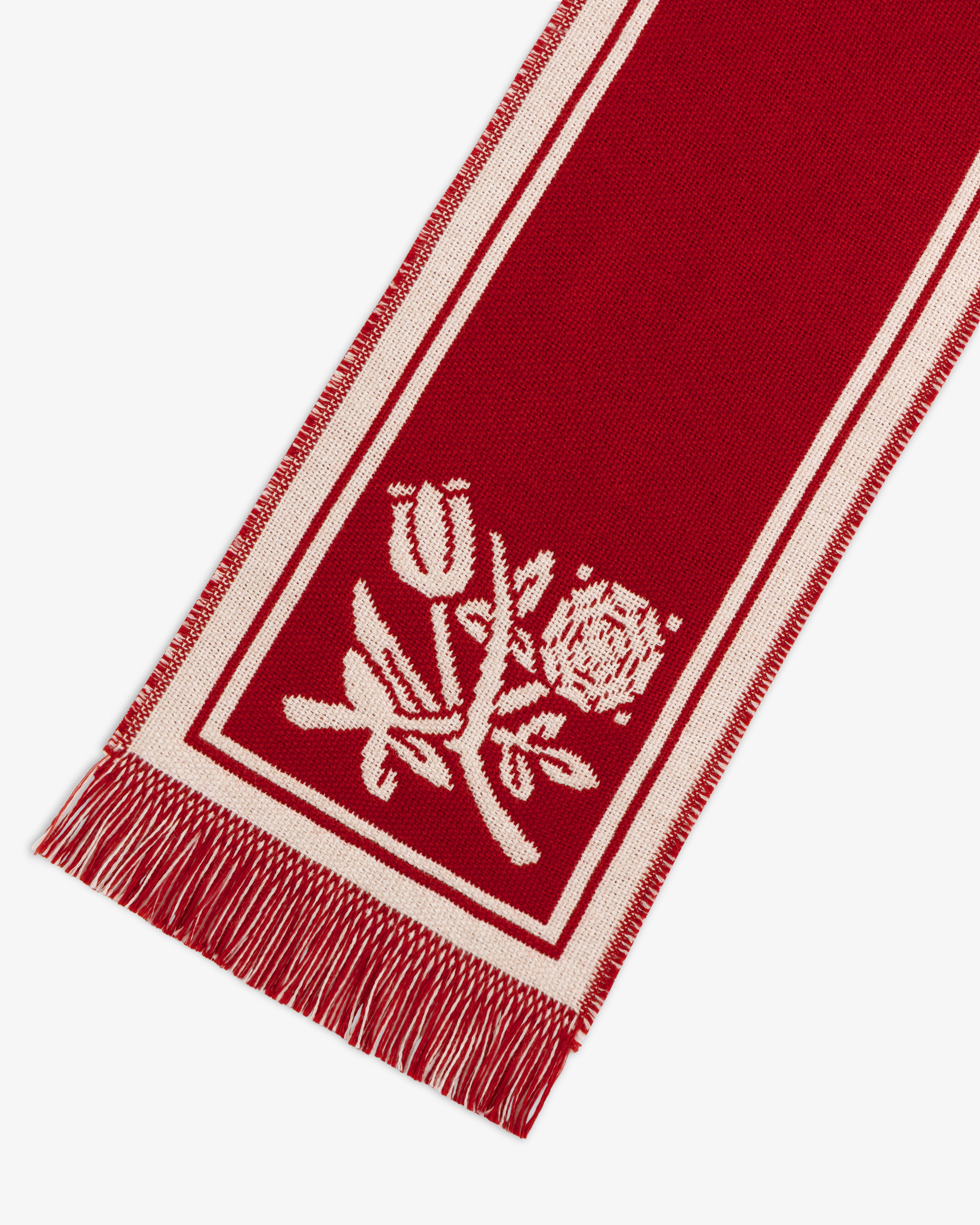 Wool Script Scarf in red with white borders, fringe ends, and a woven floral motif.
