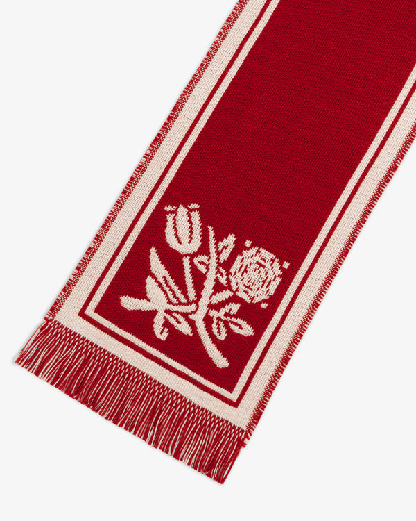 Wool Script Scarf in red with white borders, fringe ends, and a woven floral motif.