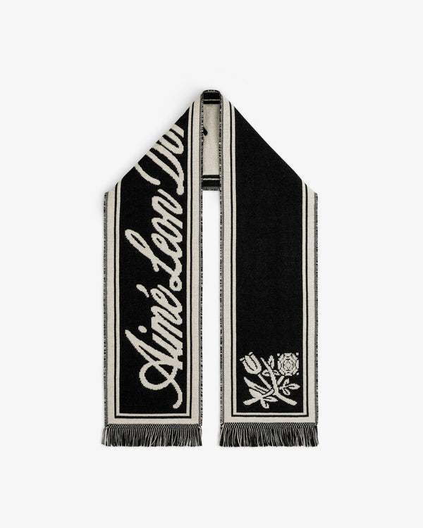 Wool Script Scarf in black and off-white with a script logo on one end, a floral graphic on the other, and fringe trim.