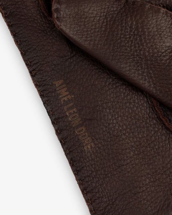 Close-up of brown Henry Gloves with an embossed brand name along the stitched edge.