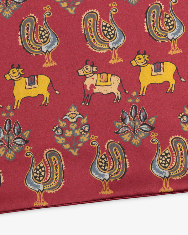 Archival Print Silk Fringe Scarf in red with a repeating pattern of yellow cows, stylized birds, and floral motifs.