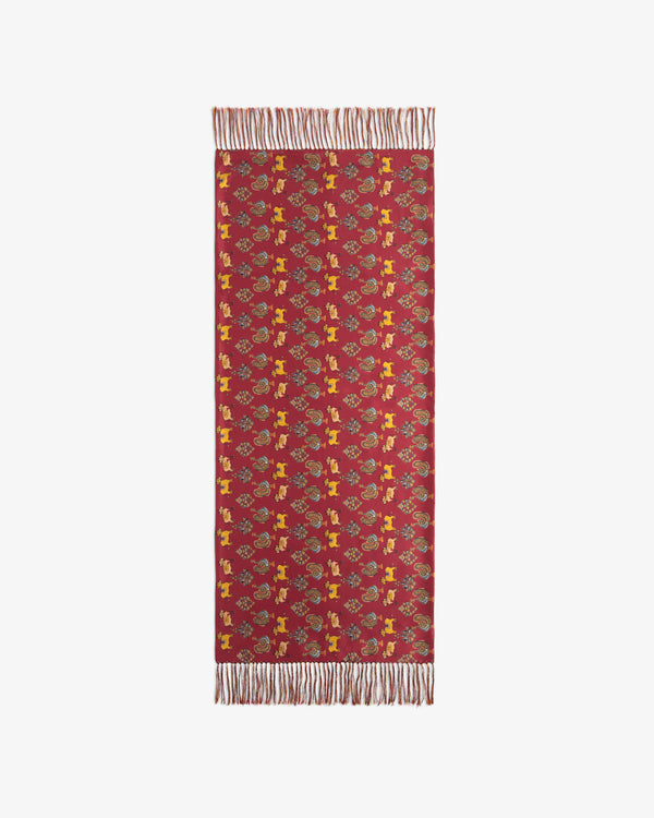 Red rectangular scarf with colorful animal and floral print and fringed ends.