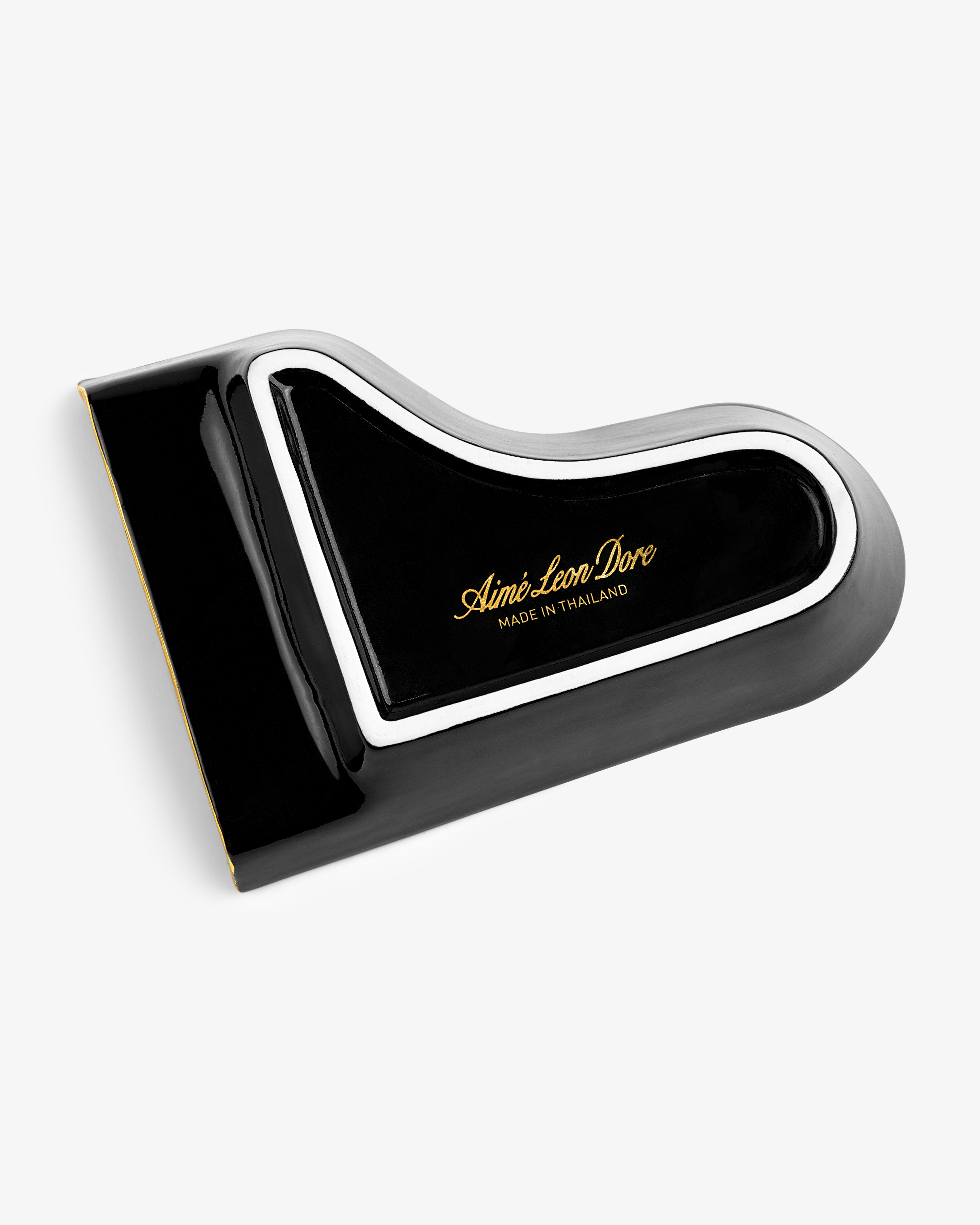 Piano Ashtray in black and white, shaped like a grand piano lid with gold “Aimé Leon Dore Made in Thailand” text.