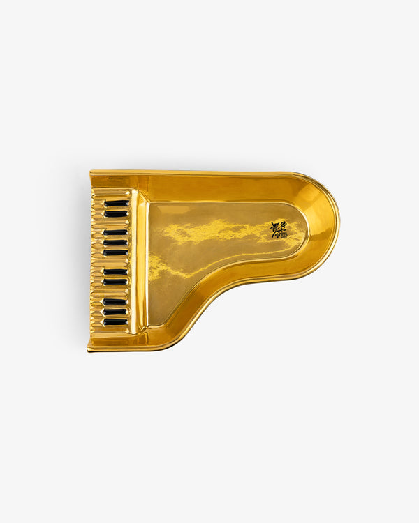 Piano Ashtray: Gold, grand piano-shaped with black keys, reflects clouds and sky on its shiny surface.