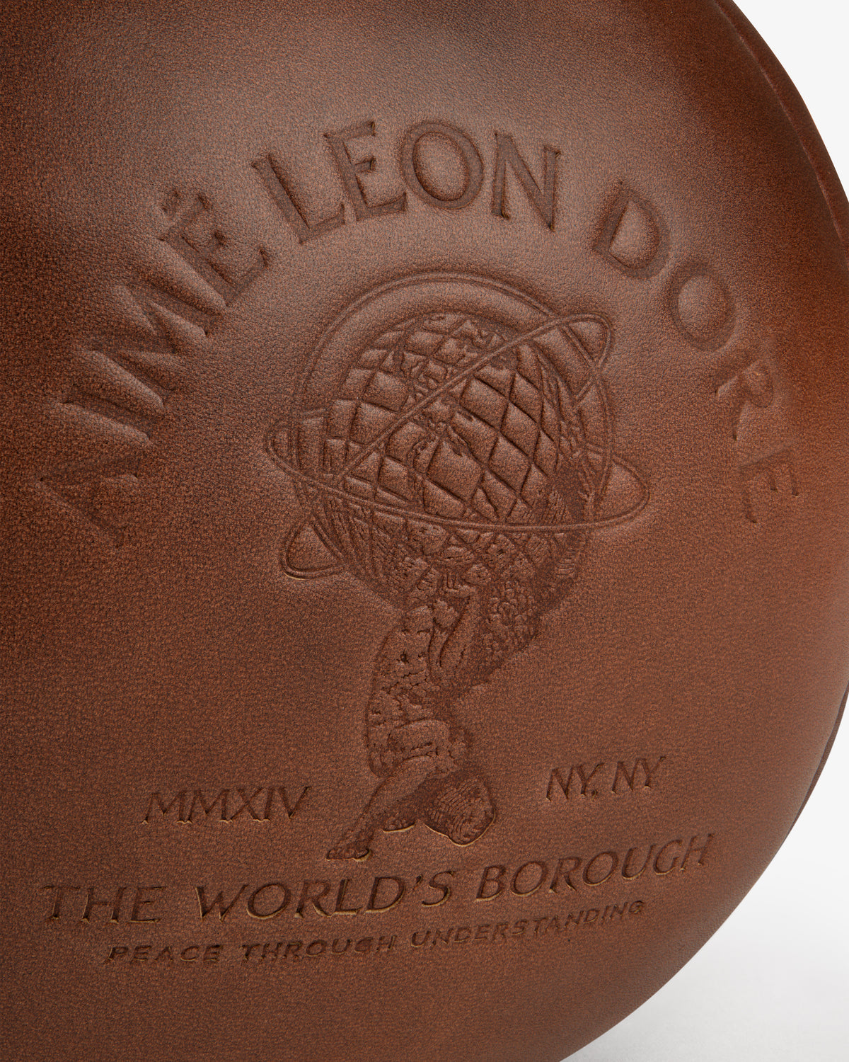 Brown leather surface of an Atlas Vintage Leather 10 Lb Kettle Bell embossed with a figure holding a globe and text.