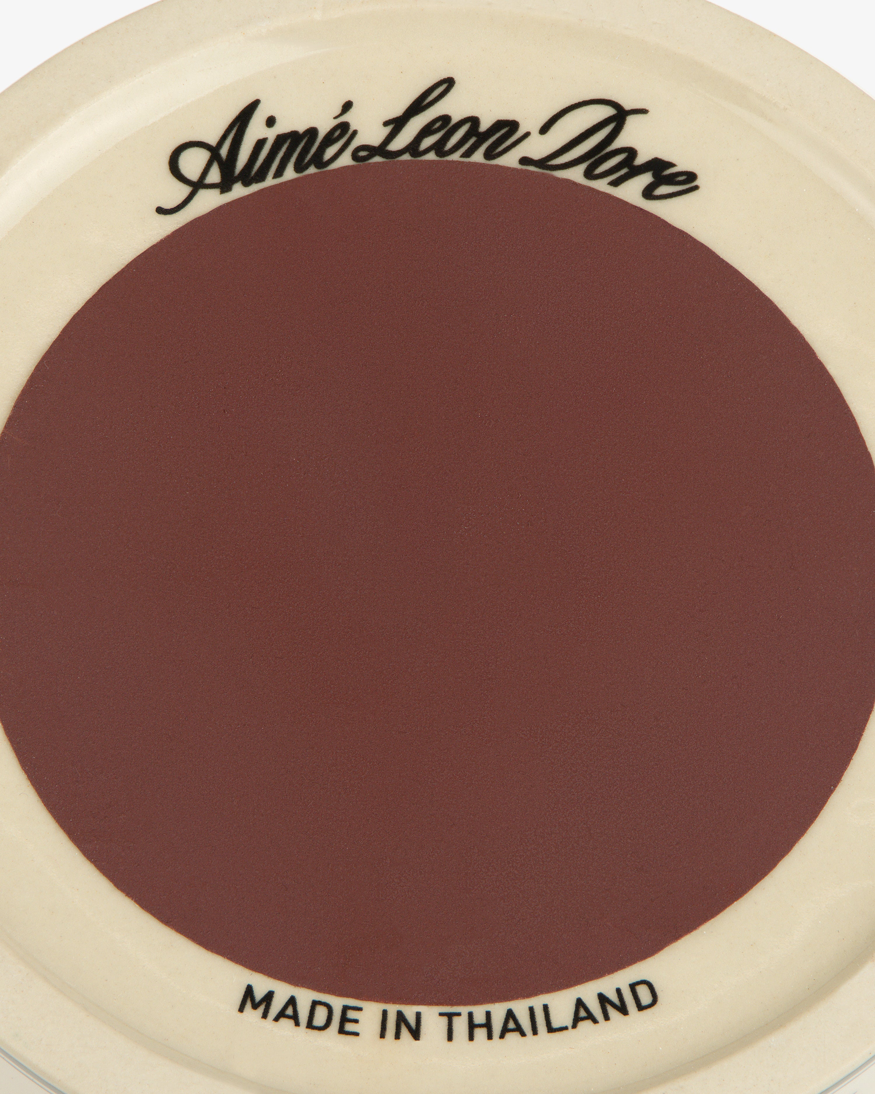 Porcelain Match Striker: maroon center, cream rim, Aimé Leon Dore on top, MADE IN THAILAND on bottom.