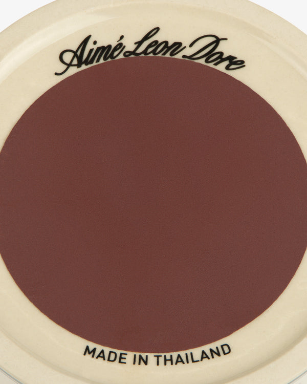 Porcelain Match Striker: maroon center, cream rim, Aimé Leon Dore on top, MADE IN THAILAND on bottom.