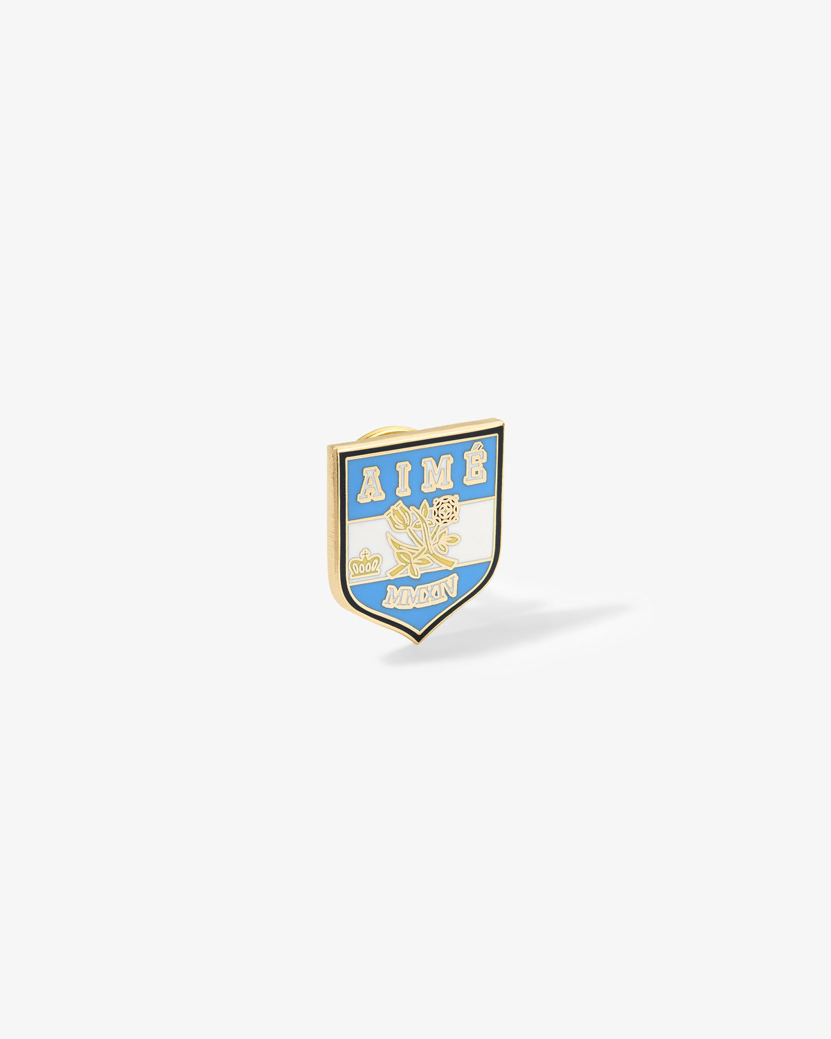 A gold and blue Graphic Pin with AIMÉ, floral design, and MONON lettering on a white shield background.