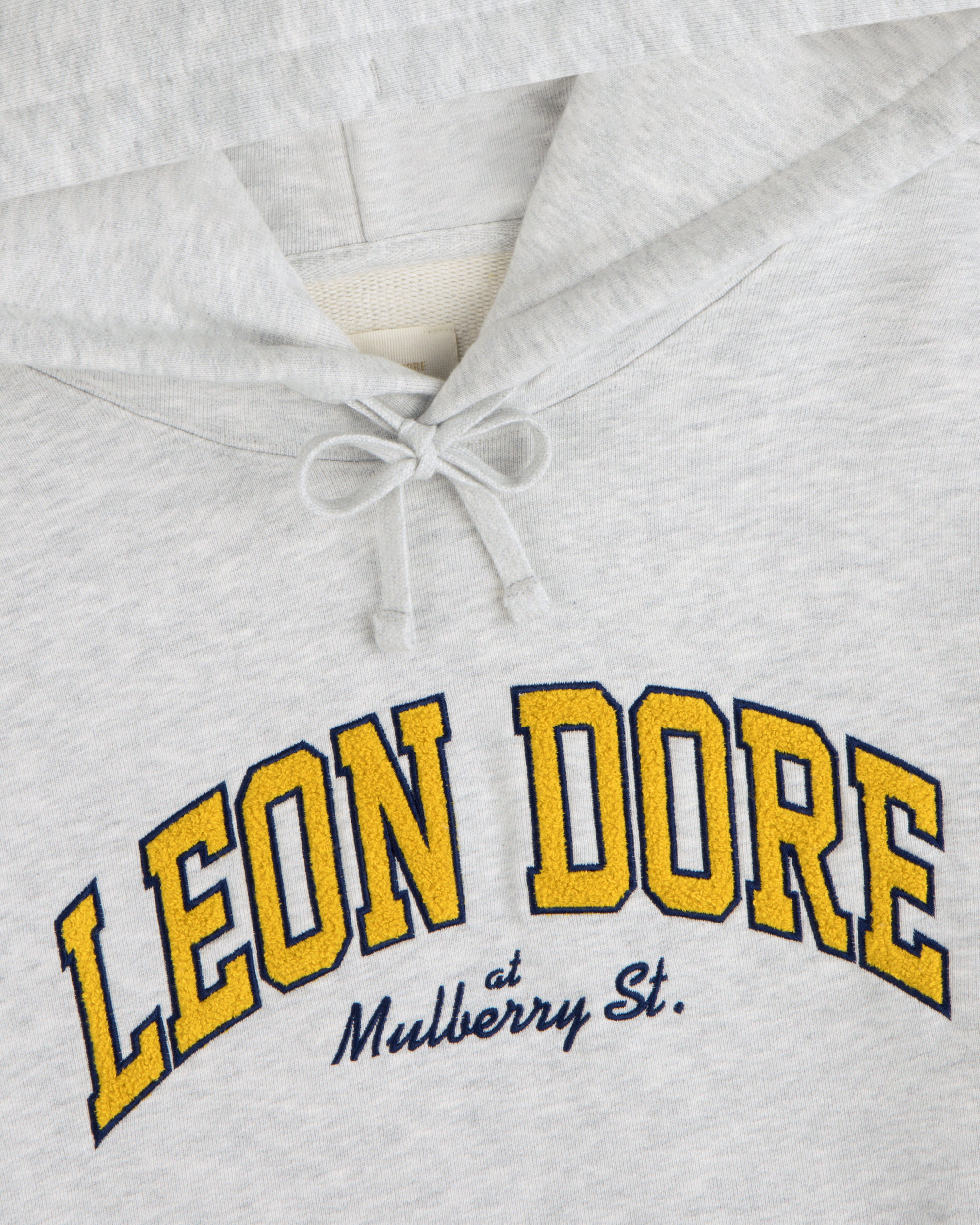 Mulberry Letterman Hoodie in light gray with “LEON DORE at Mulberry St.” printed on chest in yellow and blue.