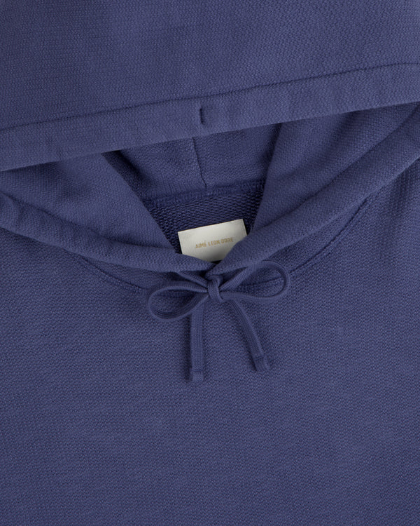 Close-up of the Stone Washed Marina Hoodie in purple, featuring a drawstring and visible white neck tag.