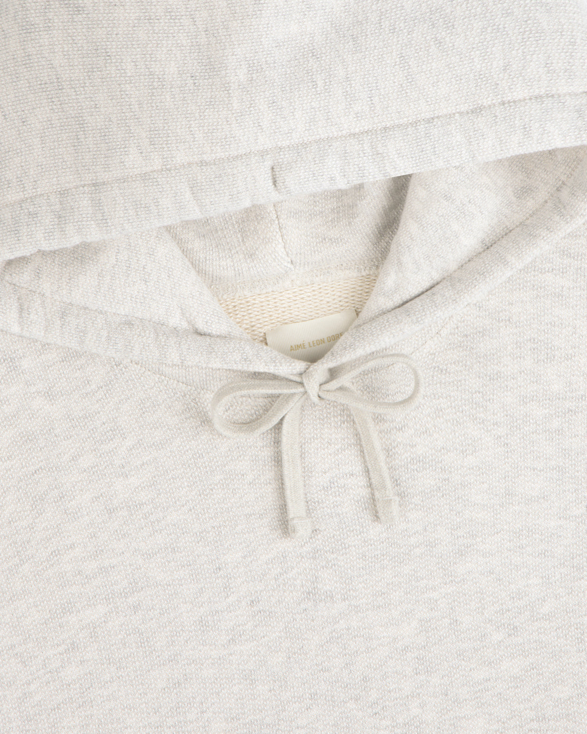 Close-up of the Stone Washed Marina Hoodie in light gray with tied drawstring and a clothing label inside the hood.