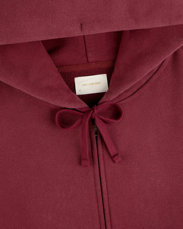 Close-up of a dark red Washed Full Zip Hoodie with drawstrings and a brand label at the neckline.