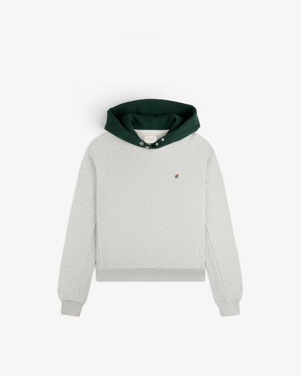 Colorblock Crest Snap Hoodie: light grey with a dark green hood, snap neckline, and a small flower emblem on the chest.