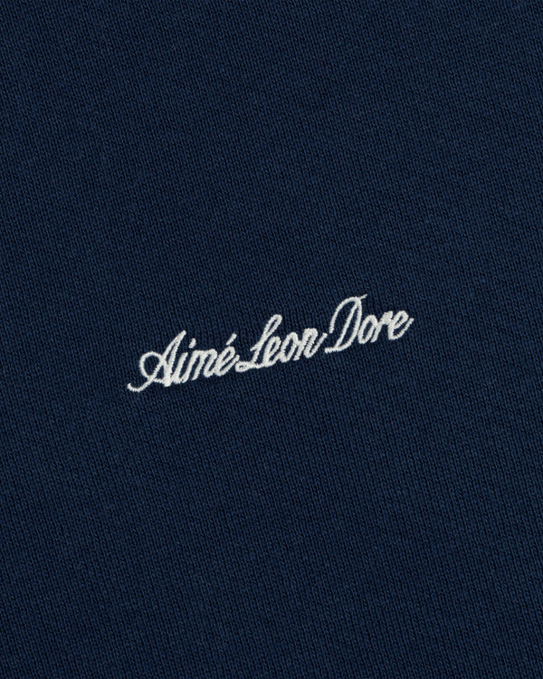 Close-up of white cursive embroidery on the dark blue fabric of a Script Full Zip Hoodie.