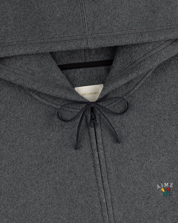 Closeup of Crest Fleece Full-Zip Hoodie in gray with black drawstring, AIME text, and a small embroidered flower.