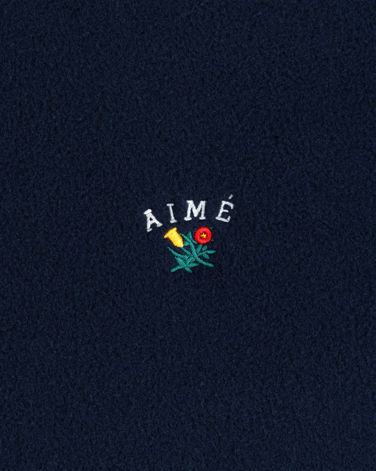 Navy Crest Fleece Full-Zip Hoodie with AIMÉ text and a small embroidered yellow-red flower with green leaves.