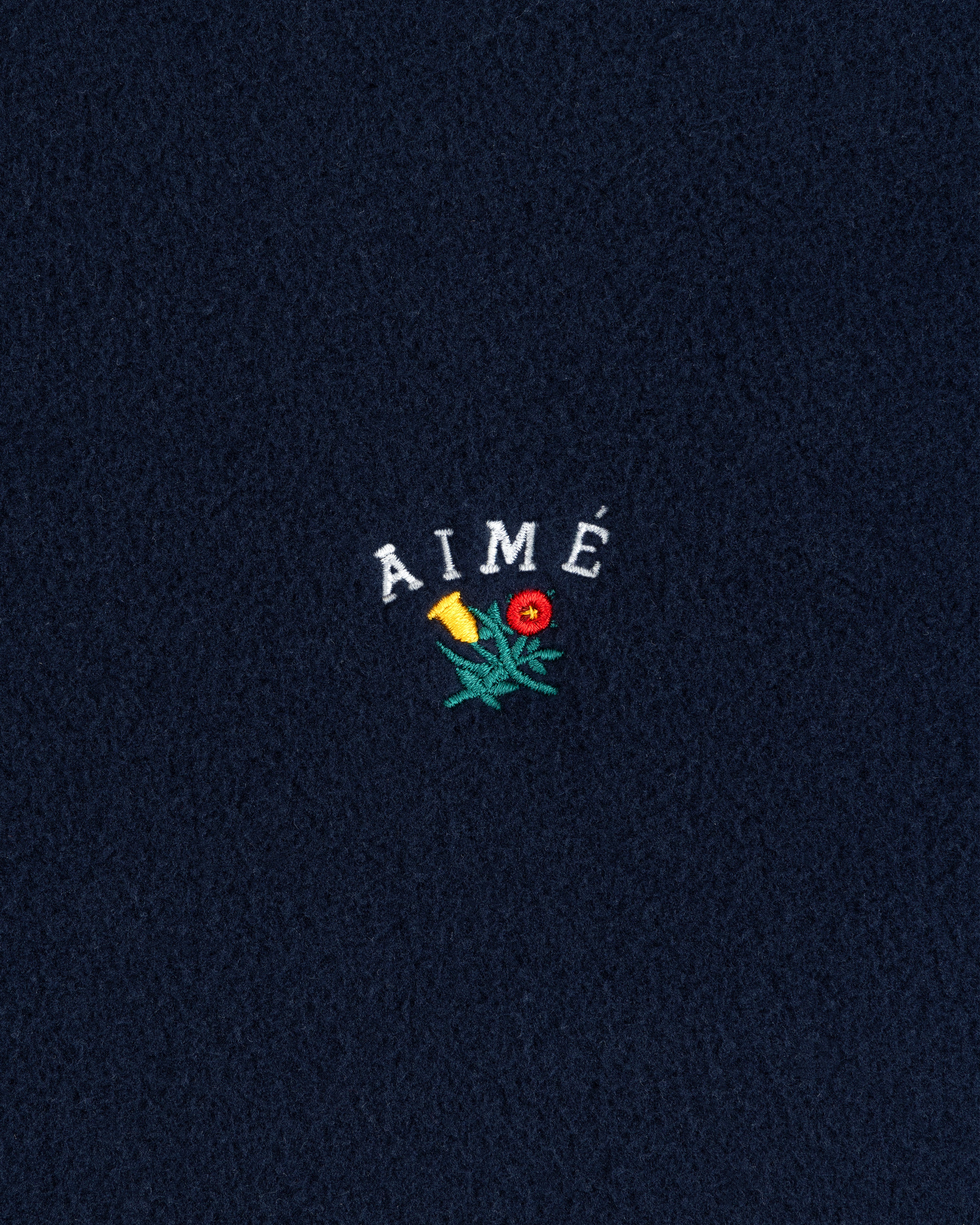 Navy Crest Fleece Full-Zip Hoodie with AIMÉ text and a small embroidered yellow-red flower with green leaves.