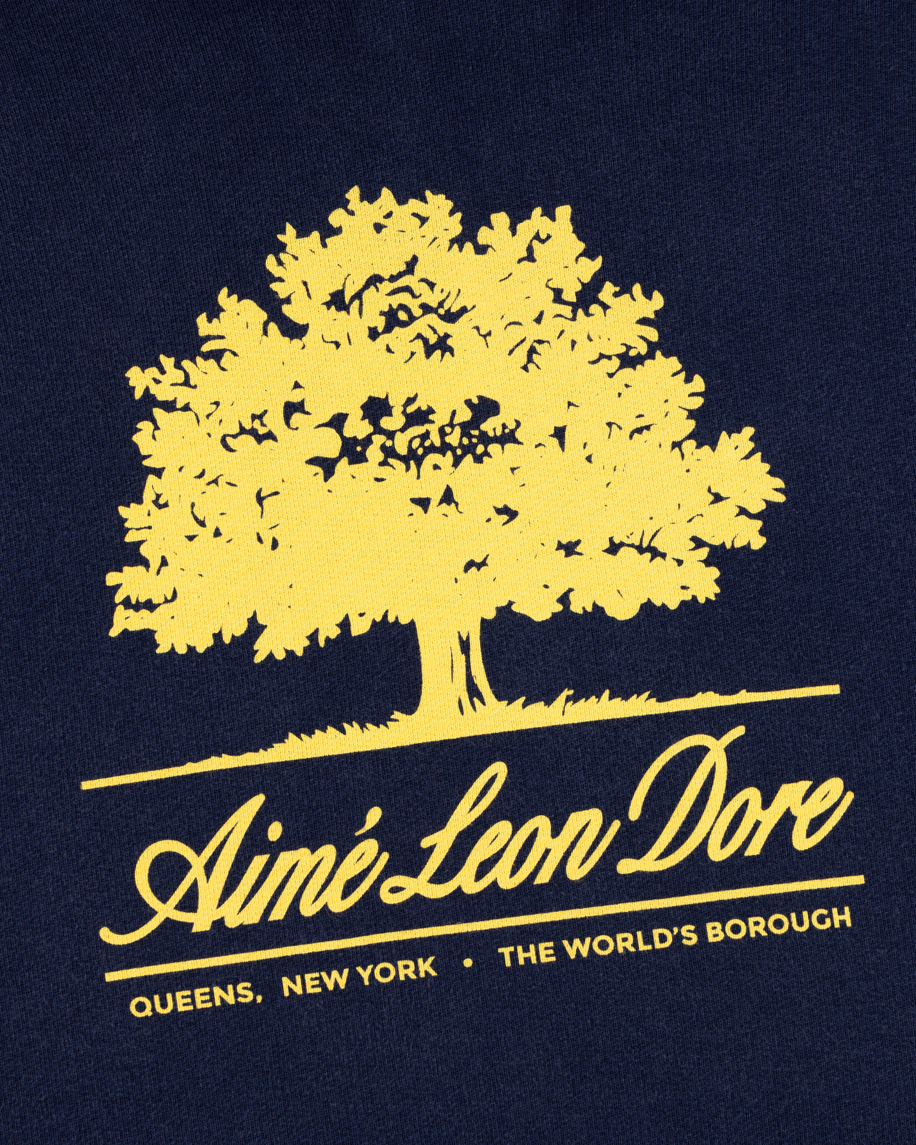 Olive Tree Hoodie with a yellow tree graphic and Aimé Leon Dore branding on dark fabric.