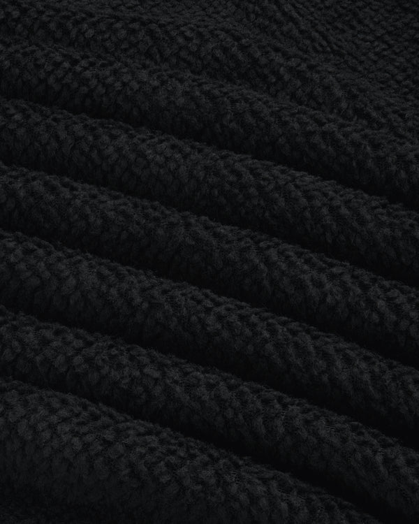 Close-up of black textured fleece fabric from a Fleece Performance Hoodie, showing diagonal folds.