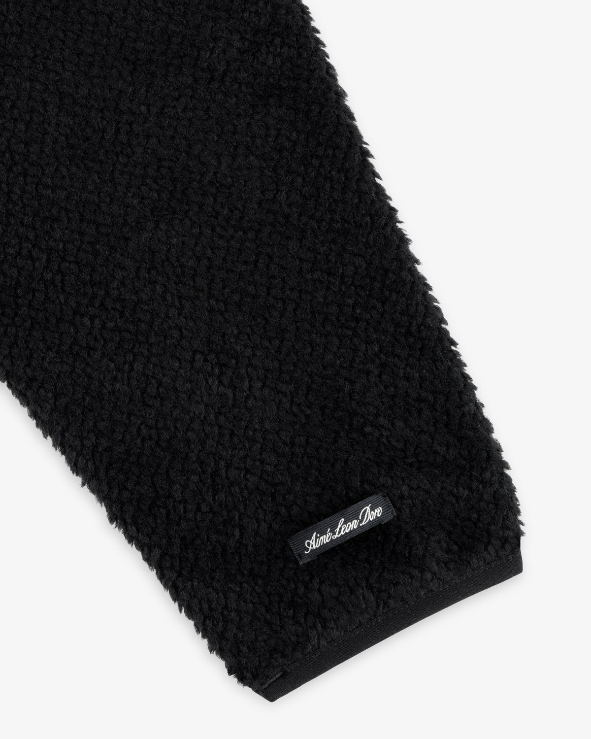 Black fleece sleeve of a Fleece Performance Hoodie with a small black brand label at the cuff.