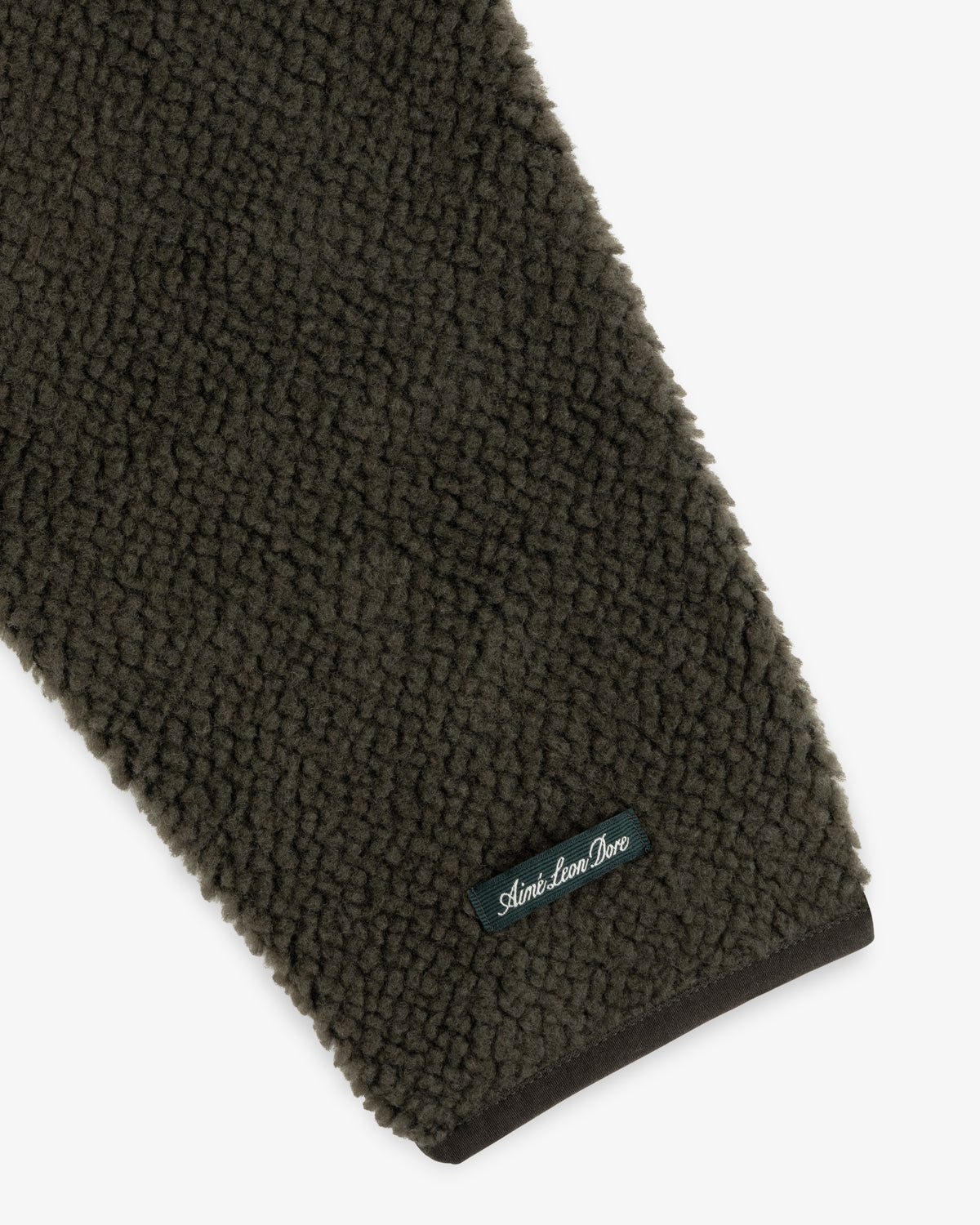 Dark olive green sleeve of a Fleece Performance Hoodie with a small branded patch near the cuff.