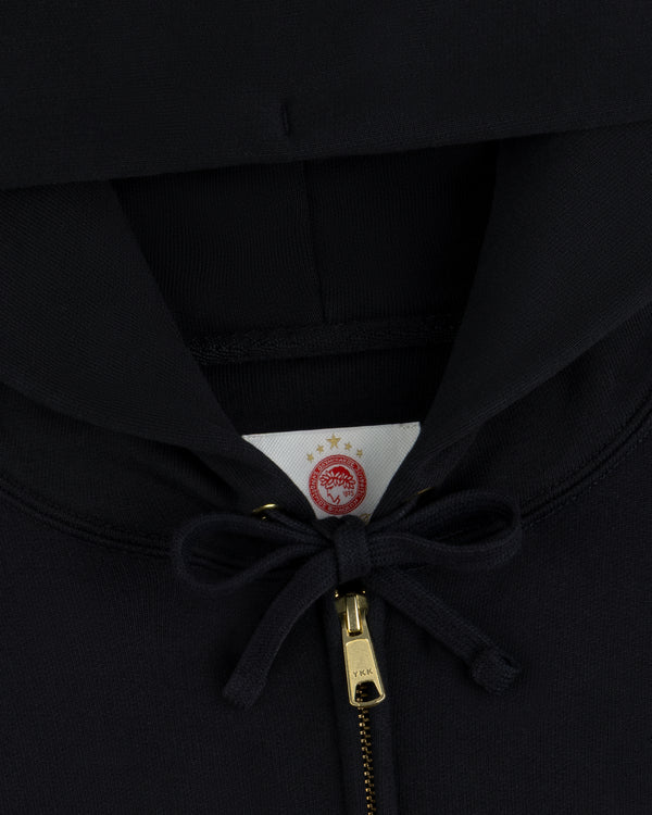 ALD / Olympiacos F.C. Full Zip Hoodie in black with a gold zipper and a circular team logo on the interior neck label.