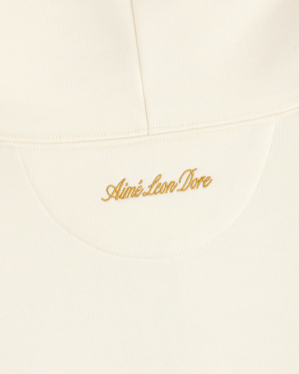 Cream-colored ALD / Olympiacos F.C. Full Zip Hoodie with gold embroidered script text on the upper back.
