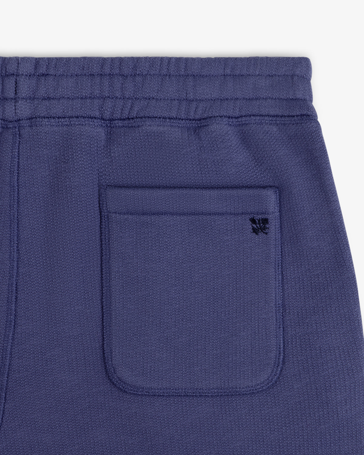 Close-up of the Stone Washed Marina Sweatpants’ purple knit pocket with a black butterfly logo above.