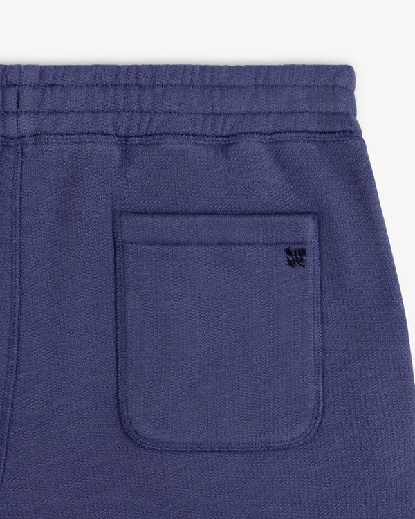 Close-up of the Stone Washed Marina Sweatpants’ purple knit pocket with a black butterfly logo above.