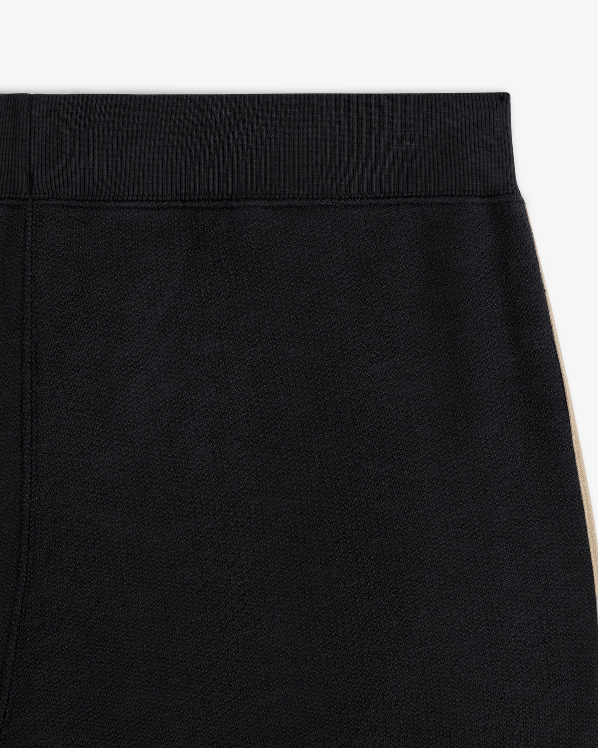 Close-up of Saint George Track Pant—black with a ribbed waistband and beige side stripe.