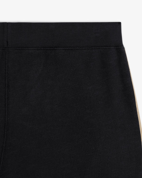Close-up of Saint George Track Pant—black with a ribbed waistband and beige side stripe.