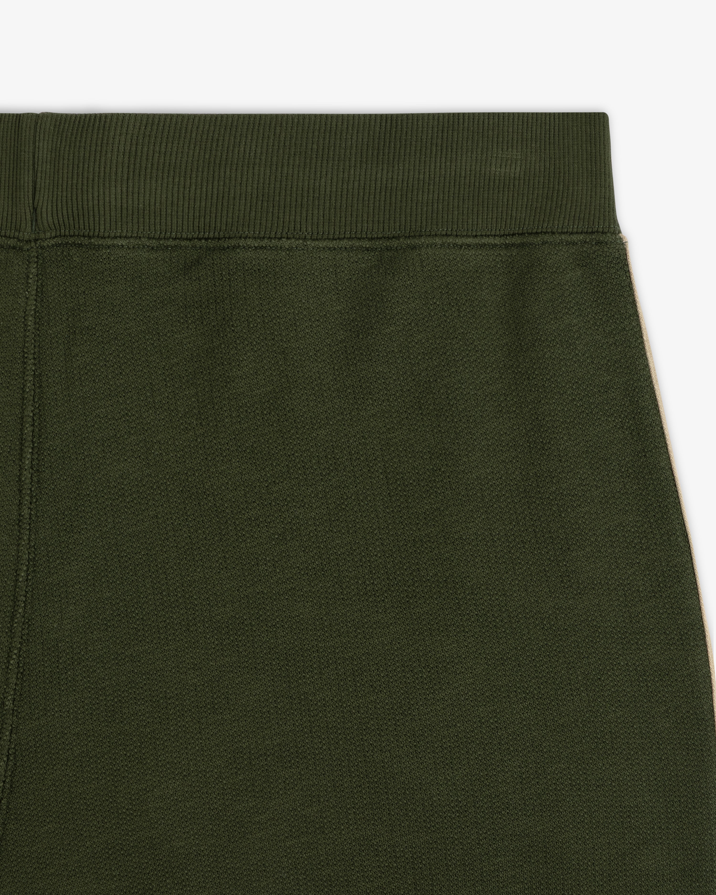 Close-up of the upper part of Saint George Track Pant in dark green with an elastic waistband.