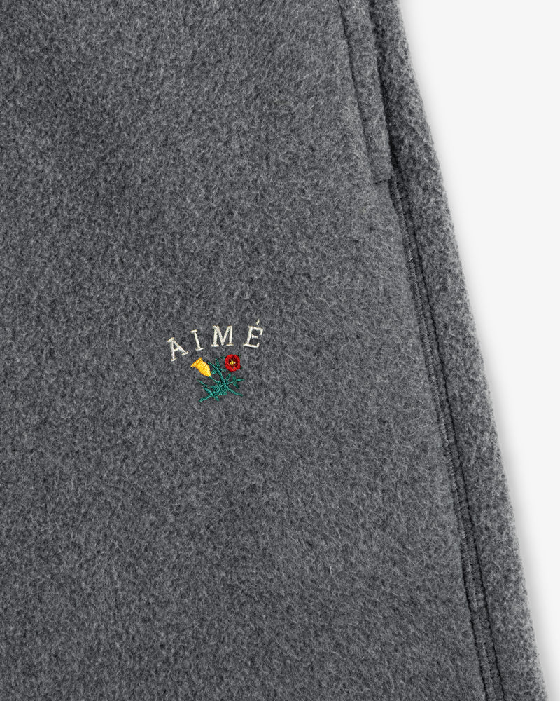 Gray wool Crest Fleece Sweatpant with AIMÉ embroidered above a small yellow and red flower with green stem.