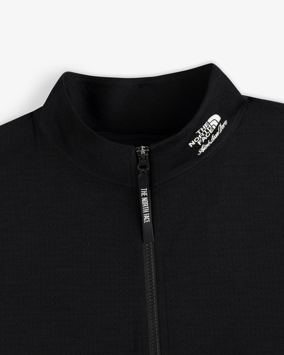 Close-up of a black ALD/The North Face DOTKNIT™ Wool Quarter Zip, logo on collar, on a white background.