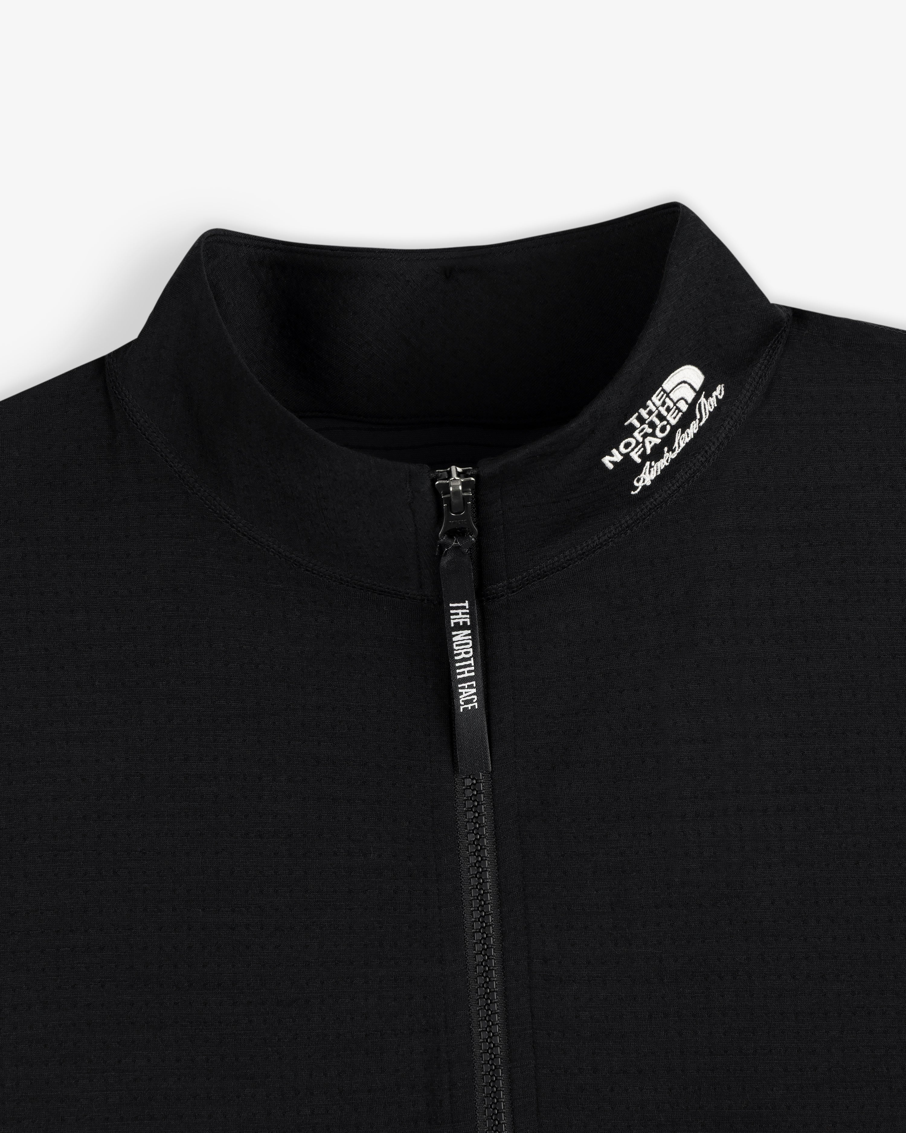 Close-up of a black ALD/The North Face DOTKNIT™ Wool Quarter Zip, logo on collar, on a white background.