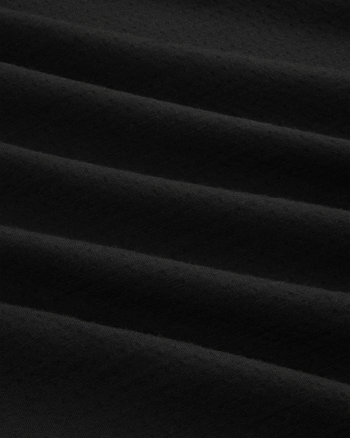 Close-up of ALD / The North Face DOTKNIT™ Wool Quarter Zip in black, showing diagonal textured folds and shadows.
