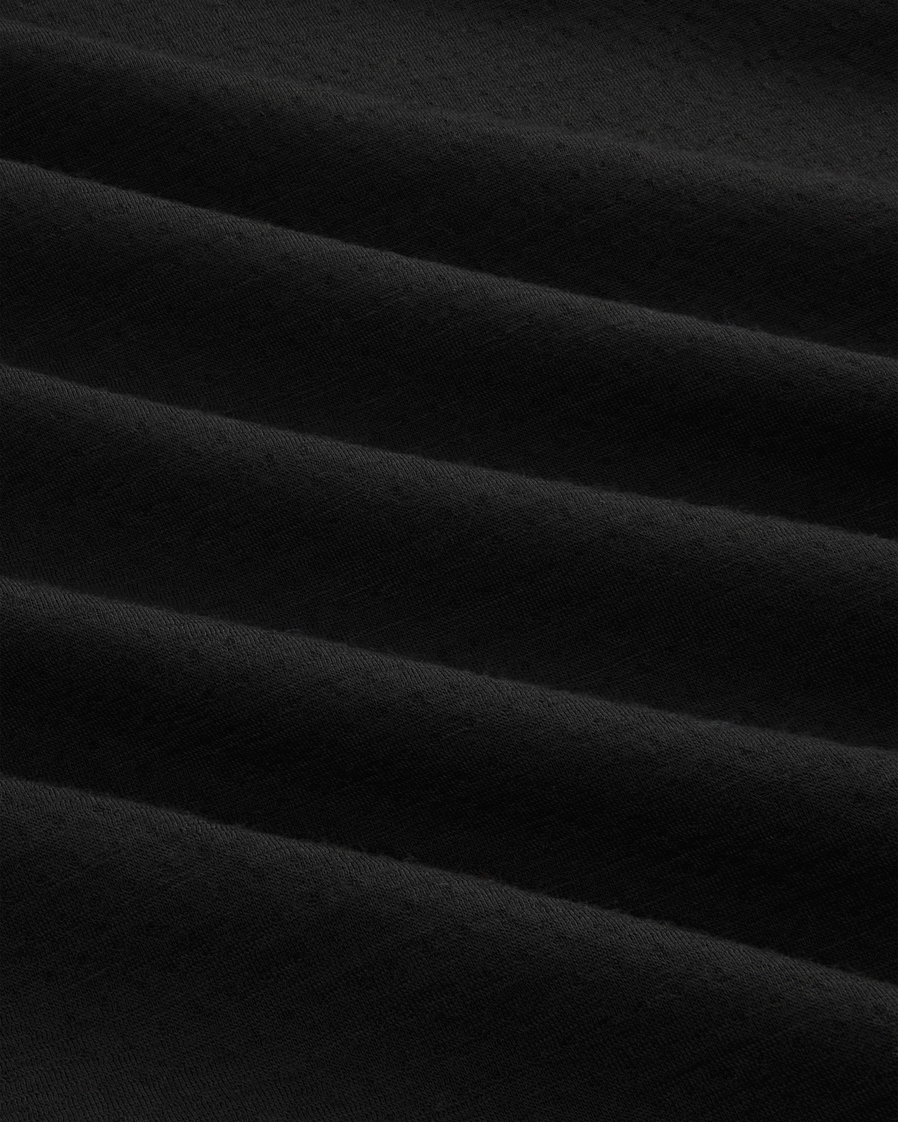 Close-up of ALD / The North Face DOTKNIT™ Wool Quarter Zip in black, showing diagonal textured folds and shadows.