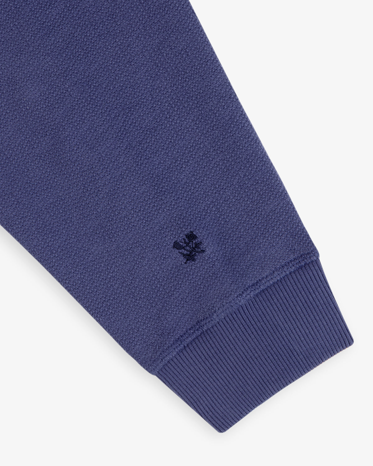 Close-up of Stone Washed Marina Crewneck Sweatshirt with blue ribbed cuff and small embroidered logo near the wrist.