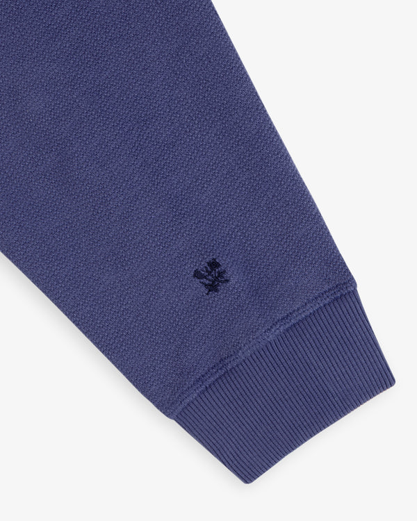 Close-up of Stone Washed Marina Crewneck Sweatshirt with blue ribbed cuff and small embroidered logo near the wrist.