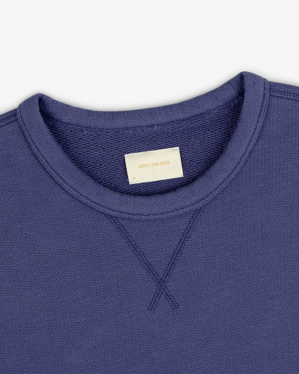 Close-up of Stone Washed Marina Crewneck Sweatshirt with visible stitching and beige Aime Leon Dore collar label.