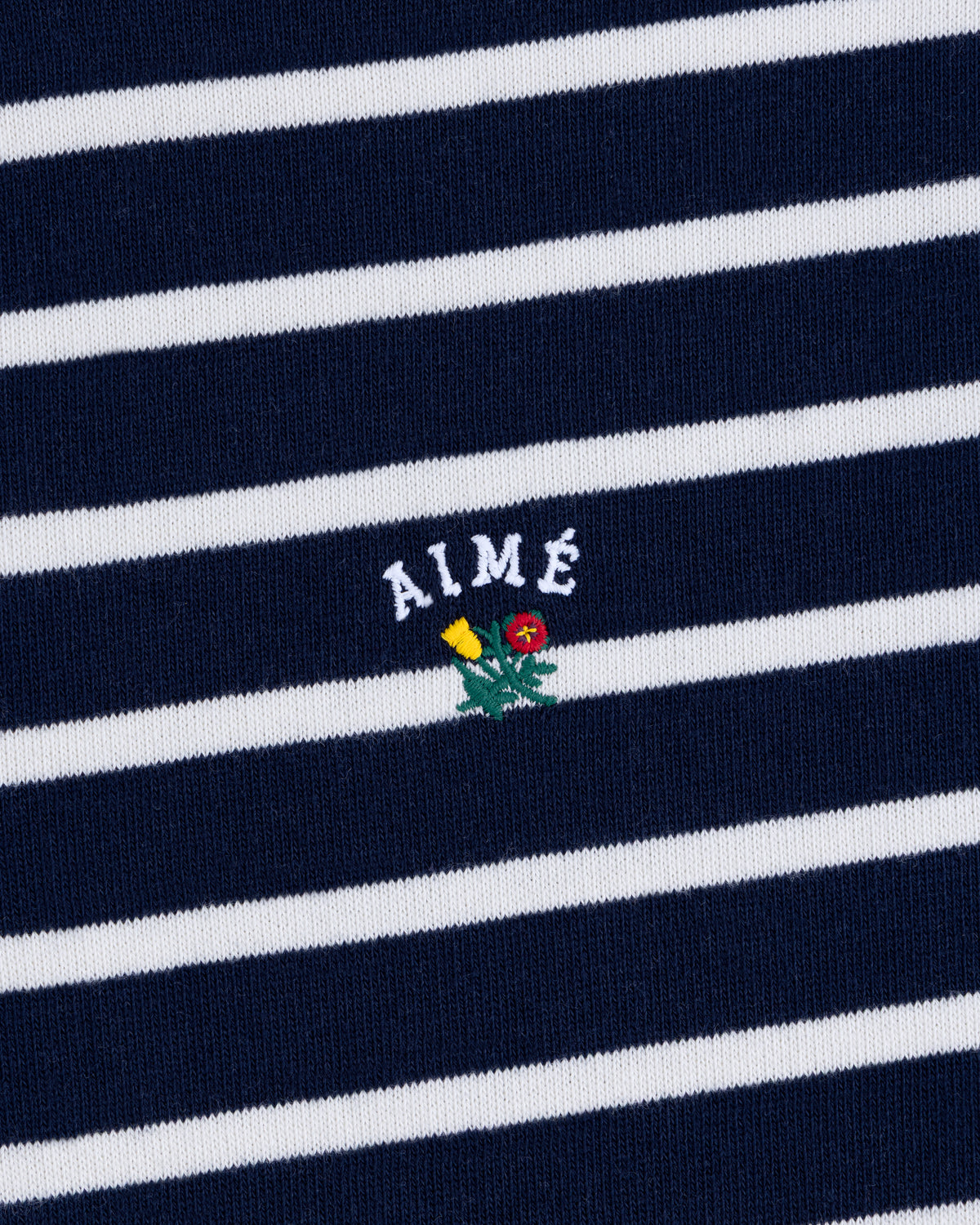 Striped Crest Quarter Zip in navy and white with AIMÉ text and a small embroidered yellow and red flower beneath.
