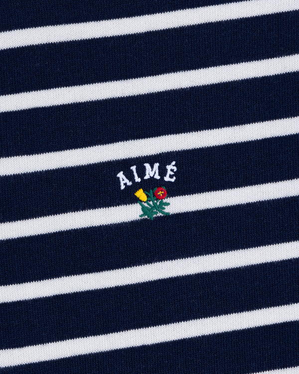 Striped Crest Quarter Zip in navy and white with AIMÉ text and a small embroidered yellow and red flower beneath.