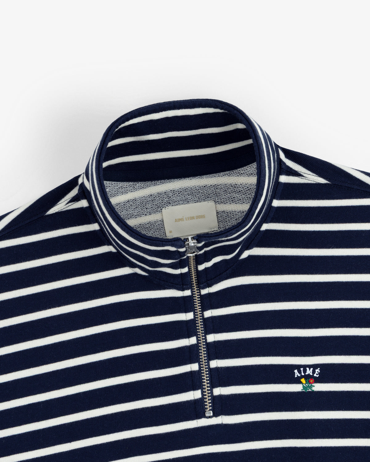 Striped Crest Quarter Zip: Navy/white stripes, AIME logo, and a small embroidered flower on the chest.