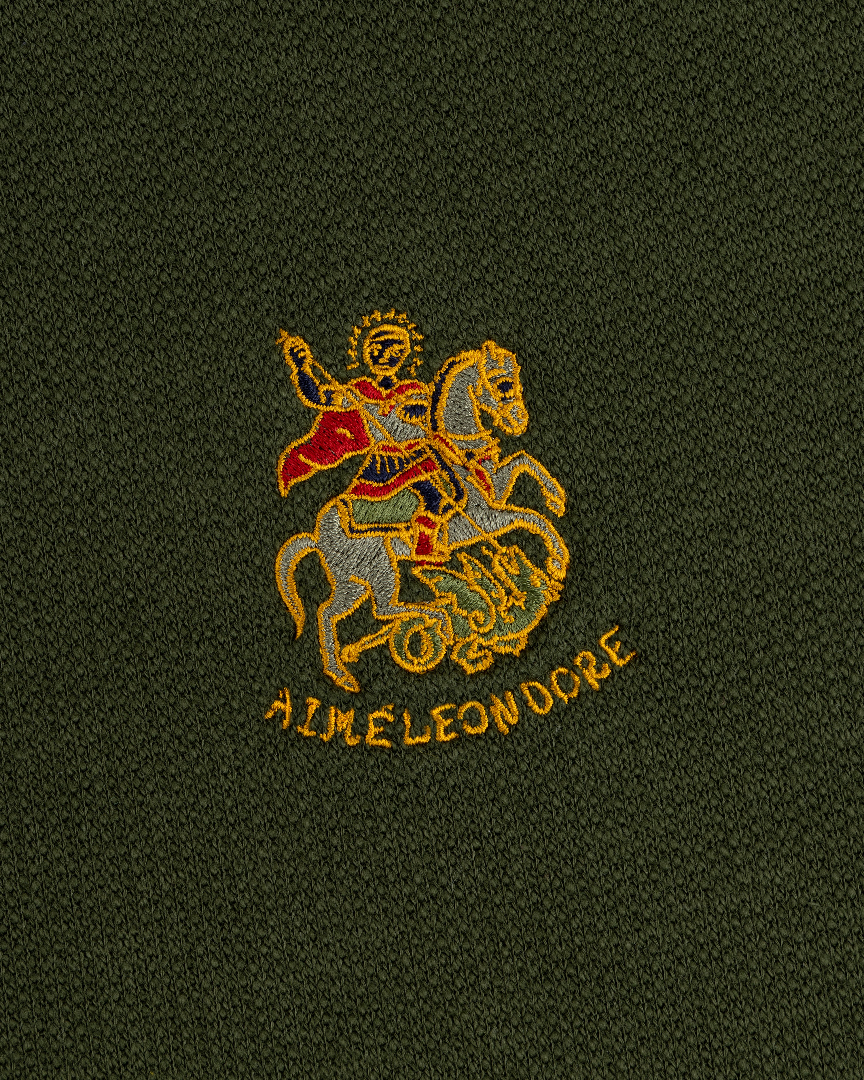 Saint George Track Jacket: Embroidered rider in red cape over yellow AIME LEON DORE text on dark green fabric.