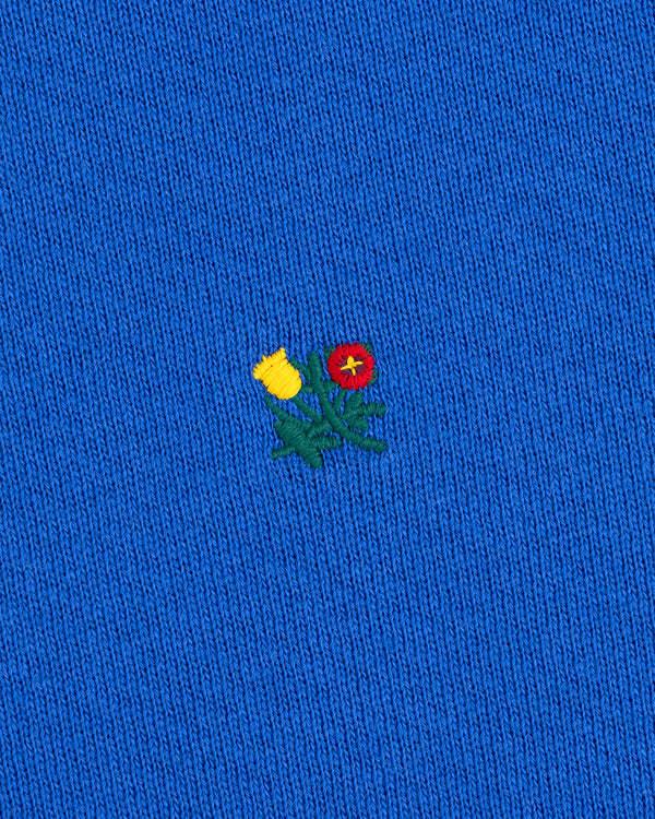 Crest Crewneck Sweatshirt in blue knit fabric featuring an embroidered patch of yellow and red flowers with green stems.
