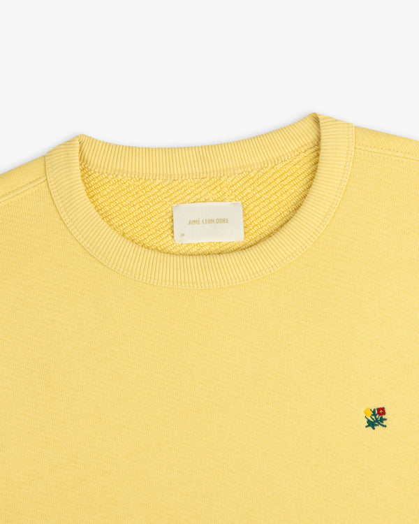 Yellow Crest Crewneck Sweatshirt with a ribbed collar and small flower embroidery on the chest.