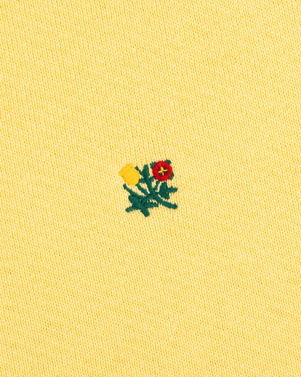 Pale yellow Crest Crewneck Sweatshirt featuring a small embroidered flower design in red, yellow, and green.