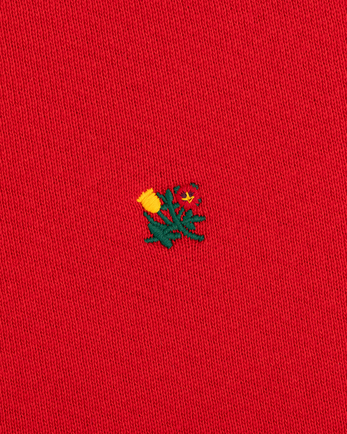 Crest Crewneck Sweatshirt in red fabric with a small embroidered yellow and green thistle design.